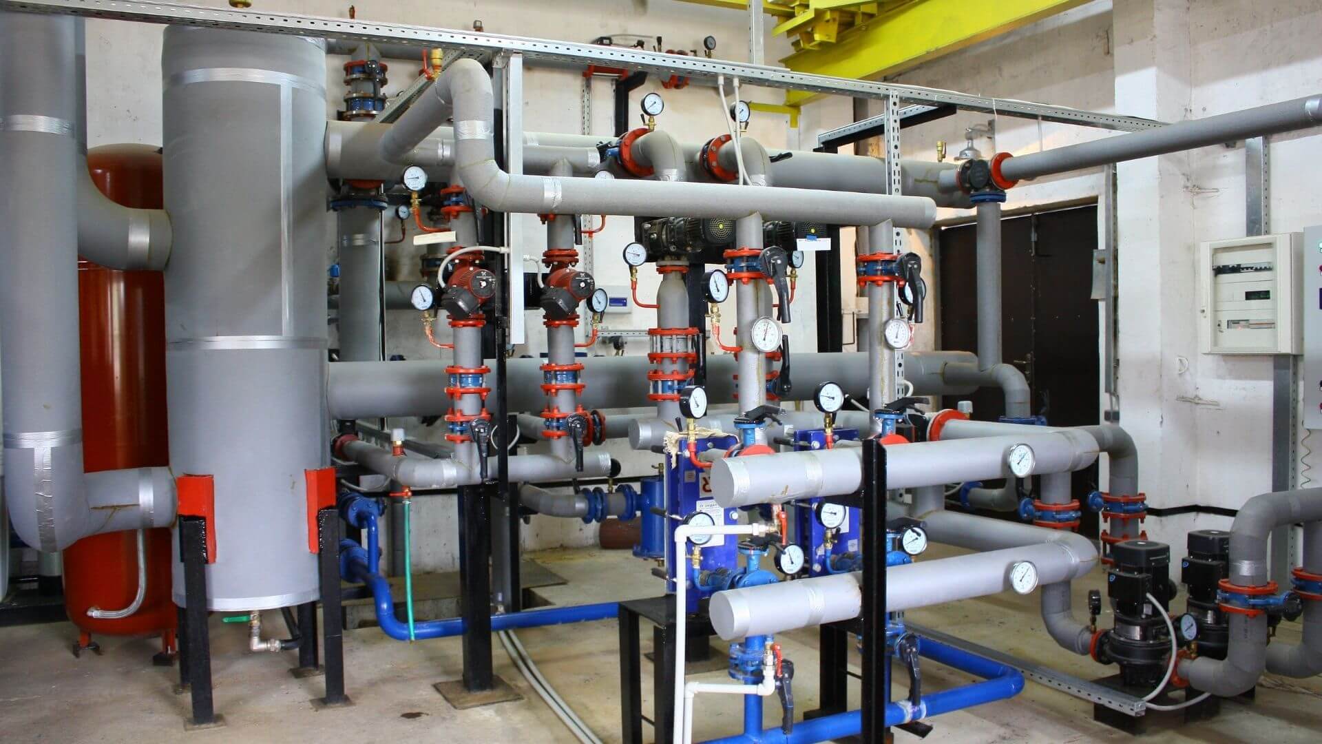 Industrial mechanical room with insulated piping and pressure gauges for closed-loop heating systems in California facility