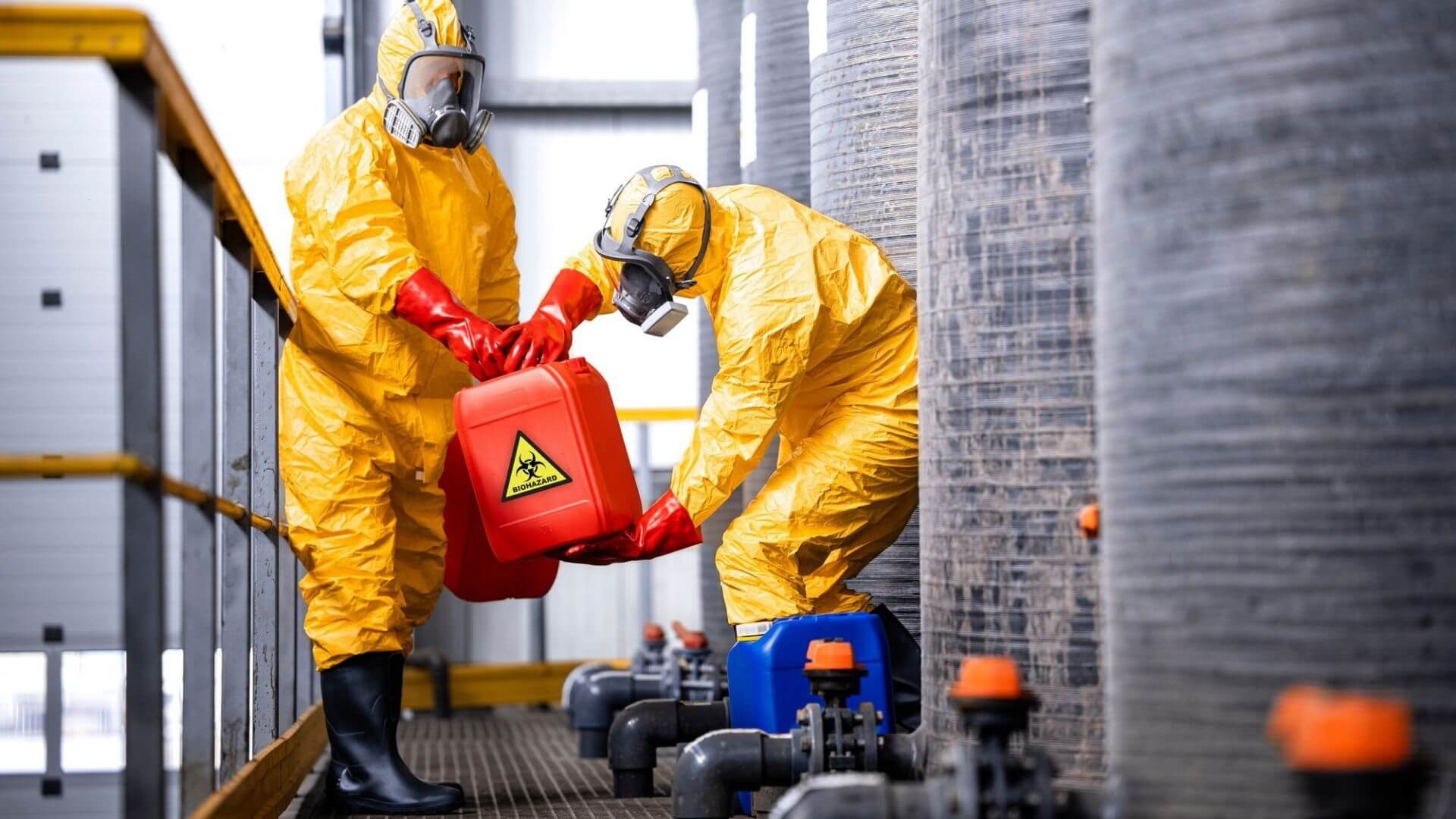 Industrial workers in protective hazmat suits handling wastewater treatment chemicals in California facility